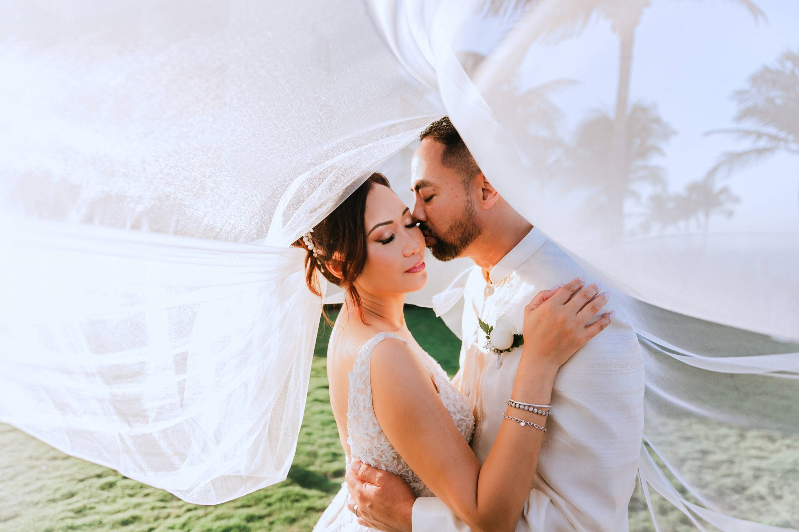 Romantic bride and groom under veil at Cancun beach during golden hour