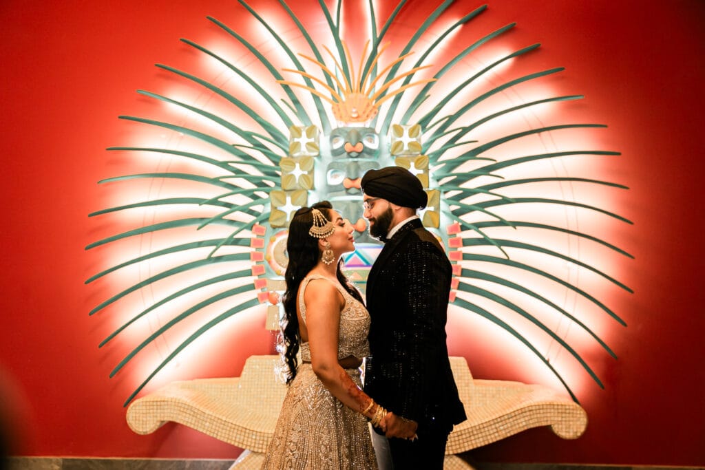 Elegant Indian couple portrait under illuminated colonnade at luxury Riviera Maya resort during evening wedding reception