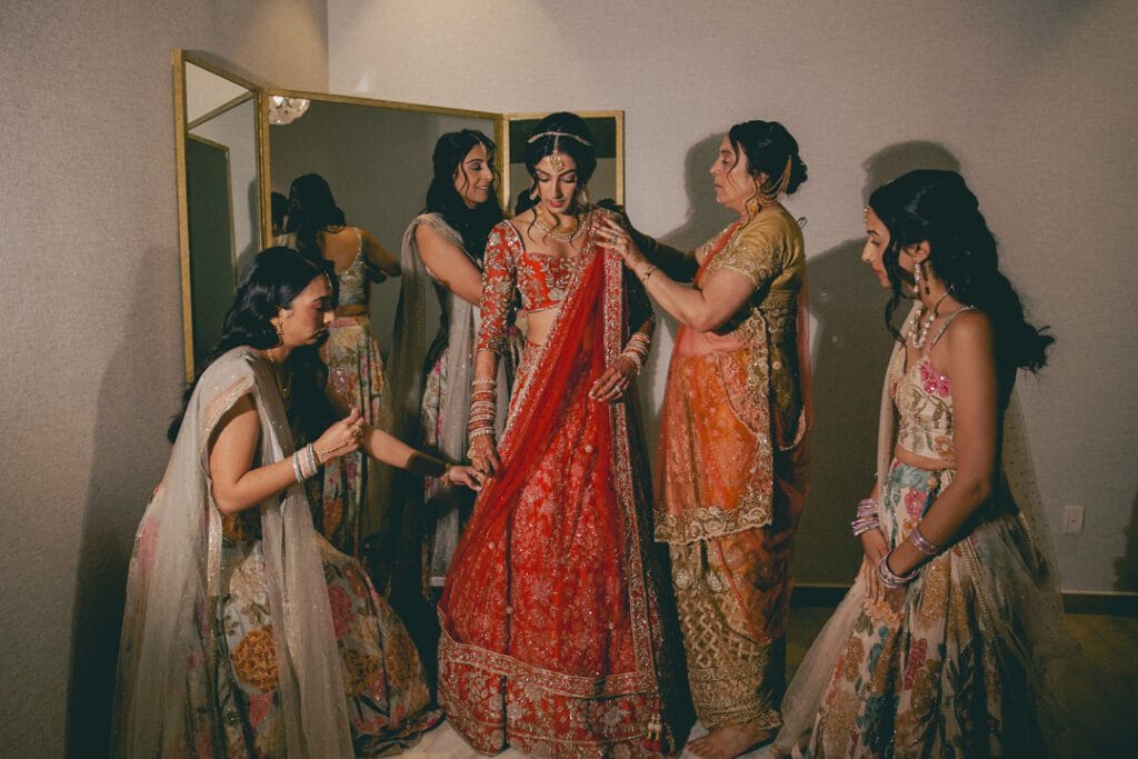 Indian bride in red lehenga getting ready with bridesmaids during bridal preparation ceremony in Riviera Maya destination wedding