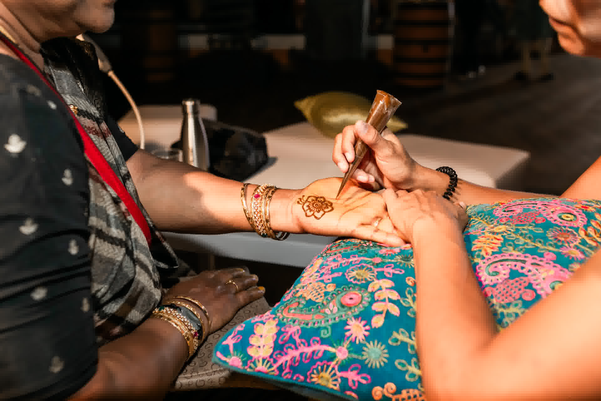 Henna artist applying a floral Mehndi design during a destination wedding celebration
