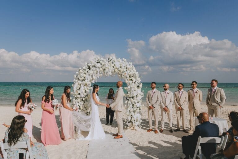 Kyle and Kishory at their beach ceremony at Dreams Natura, with guests facing the sea.