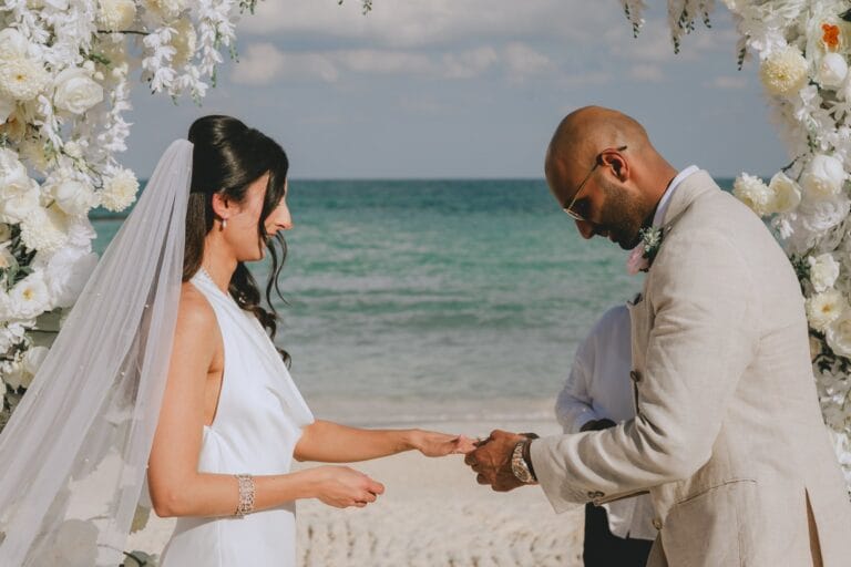 Kyle placing a ring on Kishory’s hand during their beach ceremony.