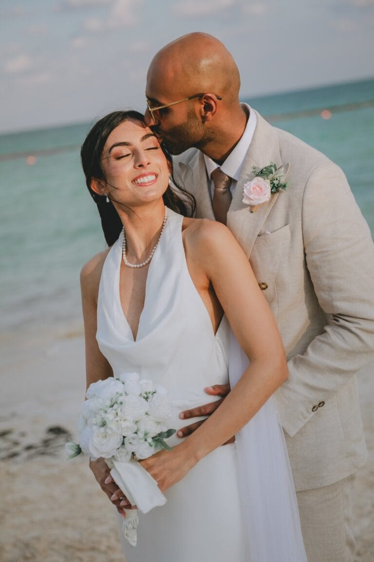 Kyle kissing Kishory’s forehead as she holds her white bridal bouquet.