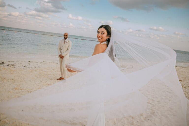 Kishory turning toward the camera as her white veil catches the sea breeze.