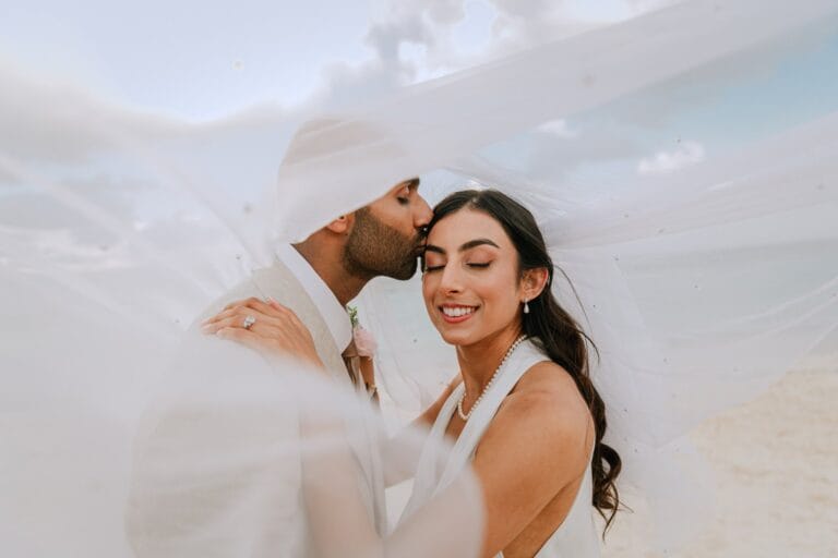 Kyle kissing Kishory’s forehead beneath her white bridal veil.