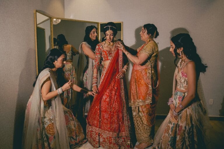 Kishory getting ready in her red lehenga with the women in her wedding party.