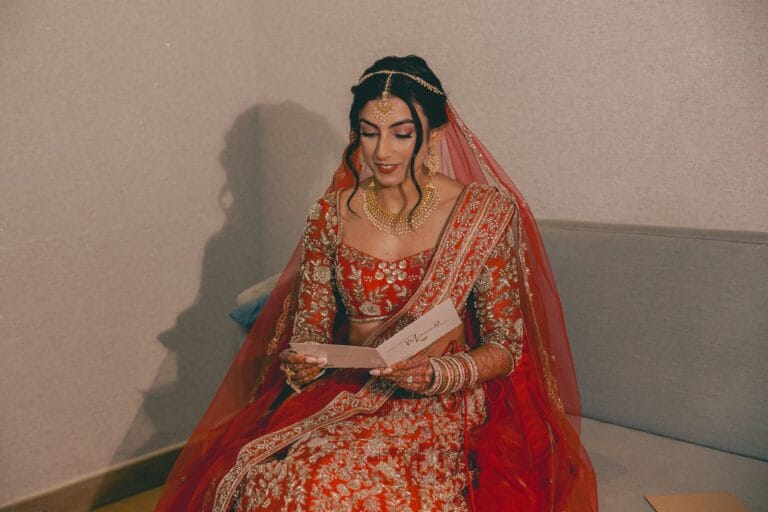 Kishory seated in her red bridal outfit, reading a handwritten note.