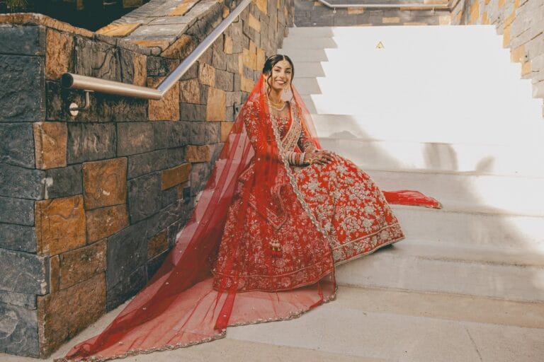 Kishory seated on a sunlit staircase with her red dupatta spread beside her.