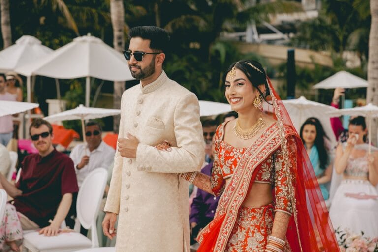 Kyle and Kishory walking together in their Indian wedding outfits at Dreams Natura.
