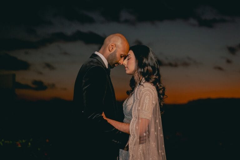 Kyle and Kishory leaning their foreheads together during a portrait at dusk.