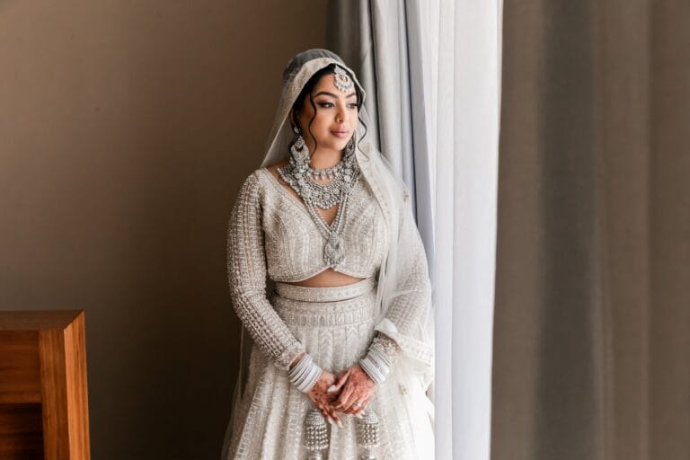 Nusaibah in her embroidered bridal outfit beside a softly lit window at Barcelo Riviera Maya.
