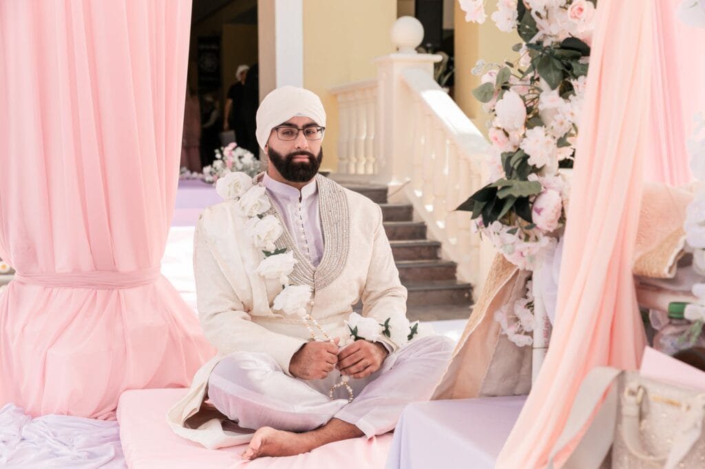 Jai seated beneath soft pink drapery at the outdoor ceremony at Barcelo Riviera Maya.