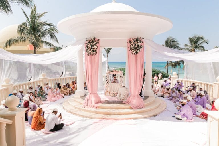 Oceanfront Sikh ceremony setting with a white gazebo and pale pink drapery at Barcelo Riviera Maya.