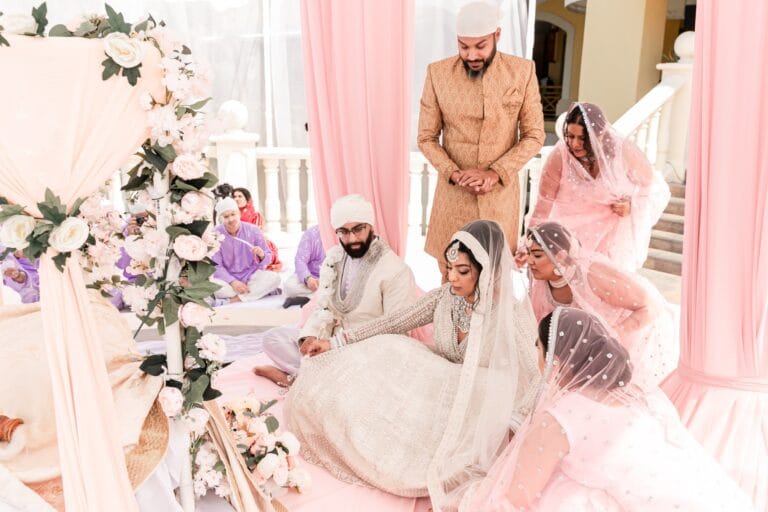 Nusaibah and Jai seated with guests beneath the ceremony gazebo at Barcelo Riviera Maya.