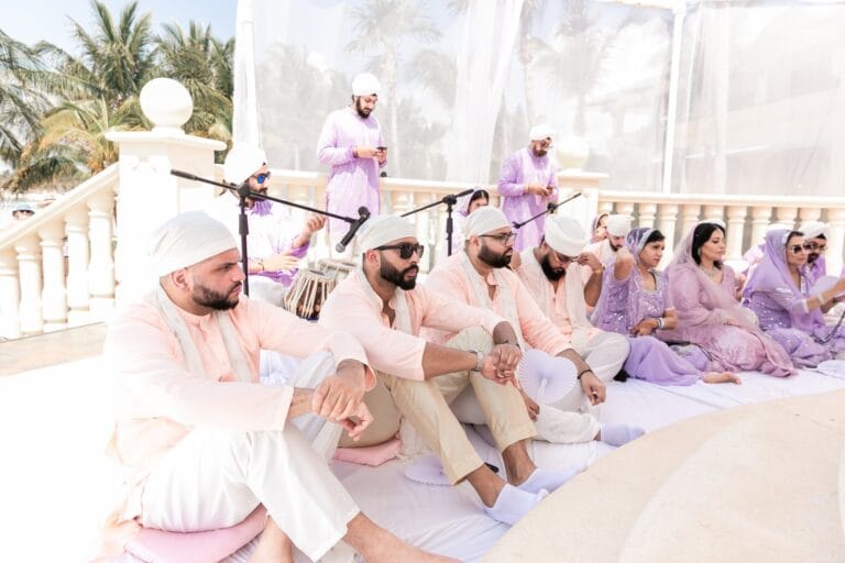 Guests and musicians beside the pale pink ceremony drapery at Barcelo Riviera Maya.