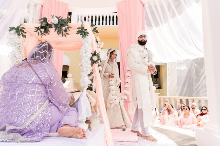 Nusaibah and Jai walking beneath the flower-decorated gazebo at Barcelo Riviera Maya.