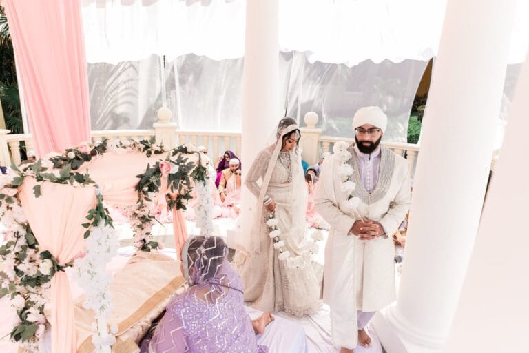 Nusaibah and Jai walking through the softly draped ceremony setting at Barcelo Riviera Maya.