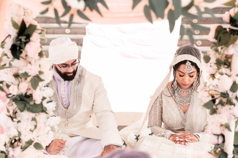 Nusaibah and Jai seated together, framed by pale flowers at Barcelo Riviera Maya.