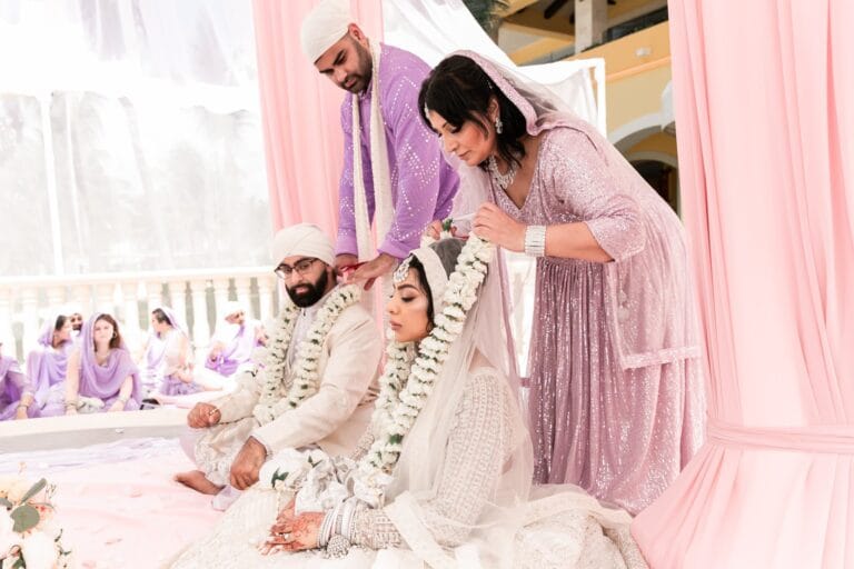 Nusaibah and Jai seated with guests beside the ceremony gazebo at Barcelo Riviera Maya.