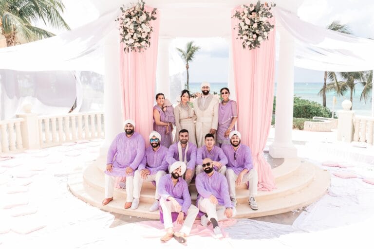 Nusaibah and Jai posing with guests in purple outfits at the gazebo at Barcelo Riviera Maya.