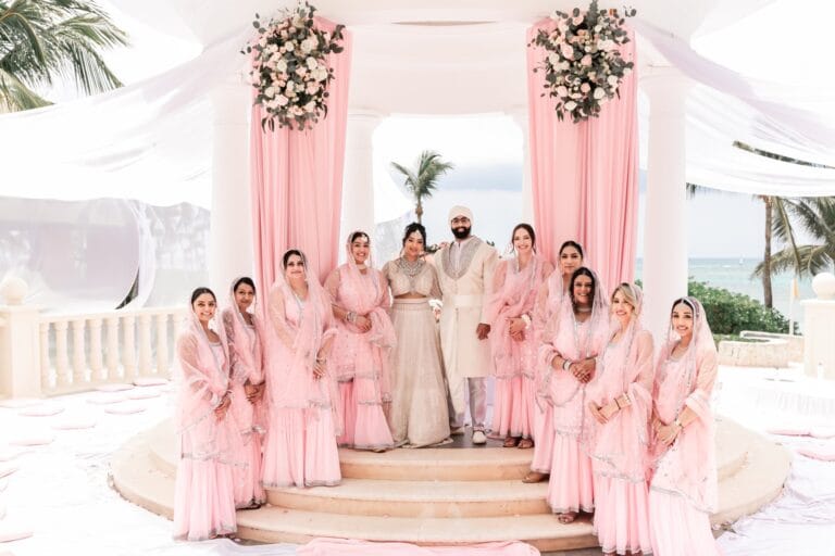 Nusaibah and Jai surrounded by the bridal party in pale pink outfits at Barcelo Riviera Maya.