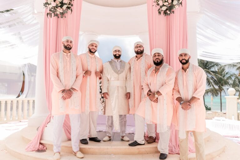 Jai standing with his wedding party in coordinated pale pink outfits at Barcelo Riviera Maya.