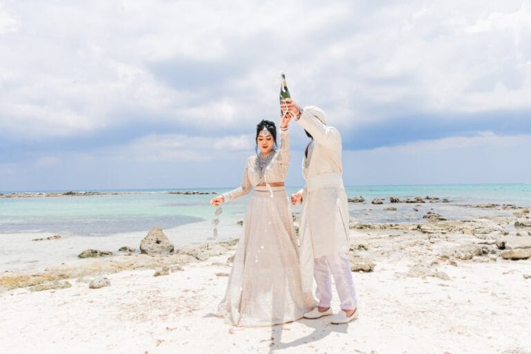 Jai raising Nusaibah's hand during their beachfront wedding portraits at Barcelo Riviera Maya.