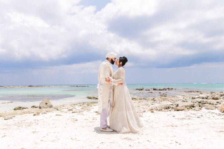 Nusaibah and Jai sharing a kiss on the beach at Barcelo Riviera Maya.