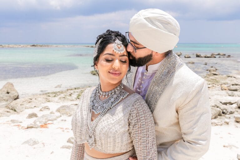 Jai kissing Nusaibah's forehead beside the Caribbean Sea at Barcelo Riviera Maya.