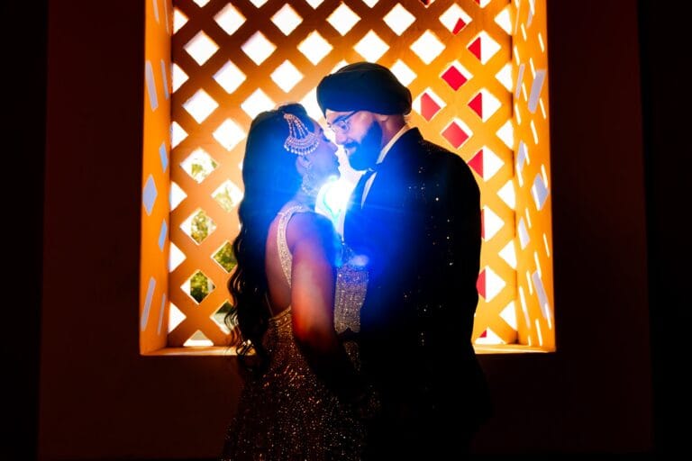Close evening portrait of Nusaibah and Jai beside a glowing lattice window at Barcelo Riviera Maya.