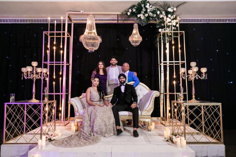 Nusaibah and Jai posing with guests at their decorated reception seating at Barcelo Riviera Maya.