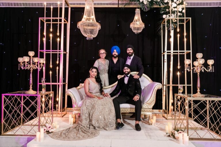 Nusaibah and Jai posing with guests beneath reception chandeliers at Barcelo Riviera Maya.