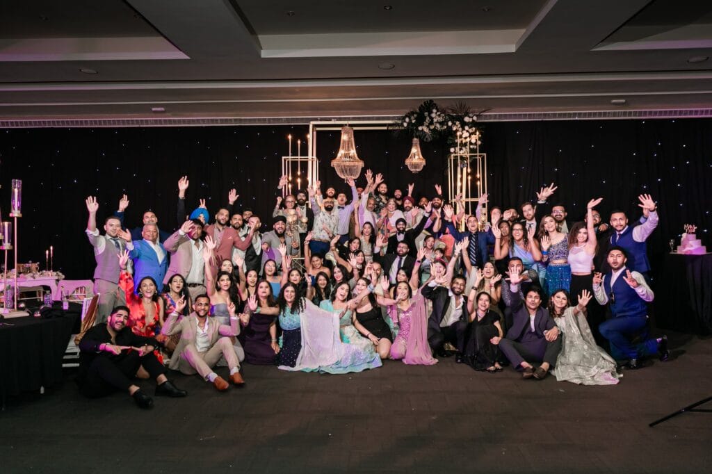 Nusaibah and Jai celebrating with a large group at their wedding reception at Barcelo Riviera Maya.