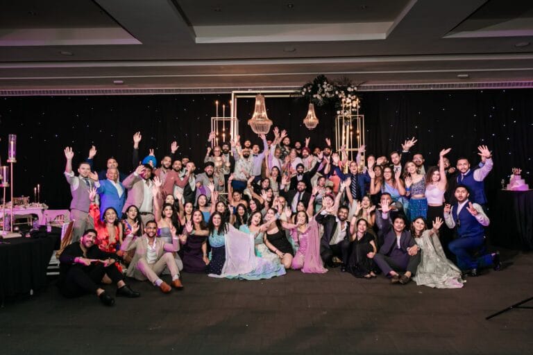 Nusaibah and Jai celebrating with a large group at their wedding reception at Barcelo Riviera Maya.
